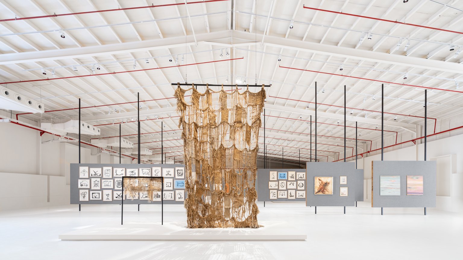 After Rain, Diriyah Contemporary Art Biennale 2024, installation view, Samia Zaru, Life is a  Woven Carpet (1995), front left, and Life is a Woven Carpet (2001), front right; multiple  works by Abdulrahman Al-Soliman and Hind Nasser in background.